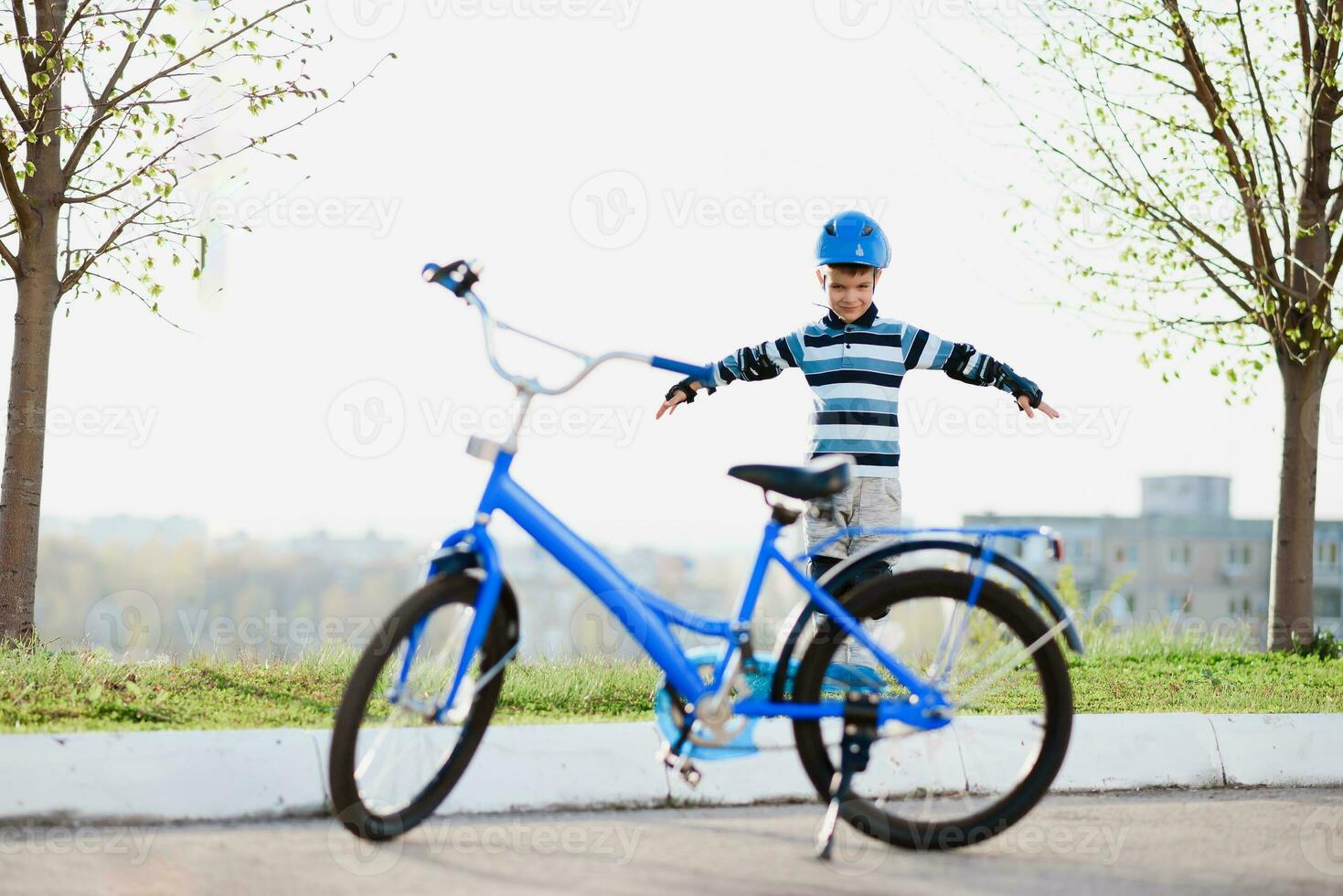 schattig kind in helm en bescherming staat in de buurt zijn fiets foto