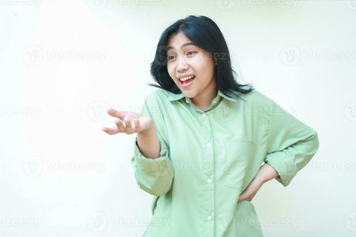 opgewonden prachtig Aziatisch vrouw vervelend groen over- grootte kleren verhogen palmen tonen presenteren gebaar op zoek weg met zelfverzekerd glimlach aanbeveling geïsoleerd Aan wit achtergrond foto