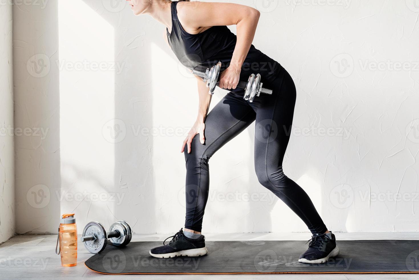 vrouw die aan het trainen is met dumbbell lifts traint haar rug en armen foto