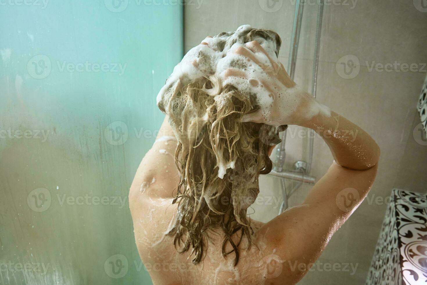 terug visie van vrouw nemen een douche in badkamer foto