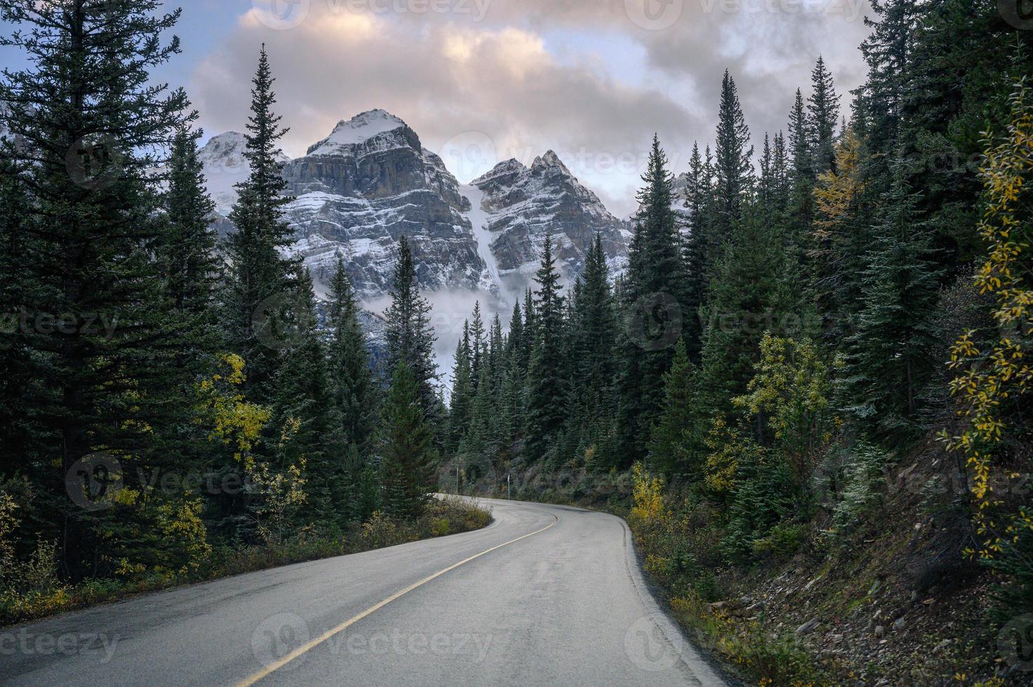 snelweg met rotsachtige bergen in dennenbos bij morenemeer in banff nationaal park foto