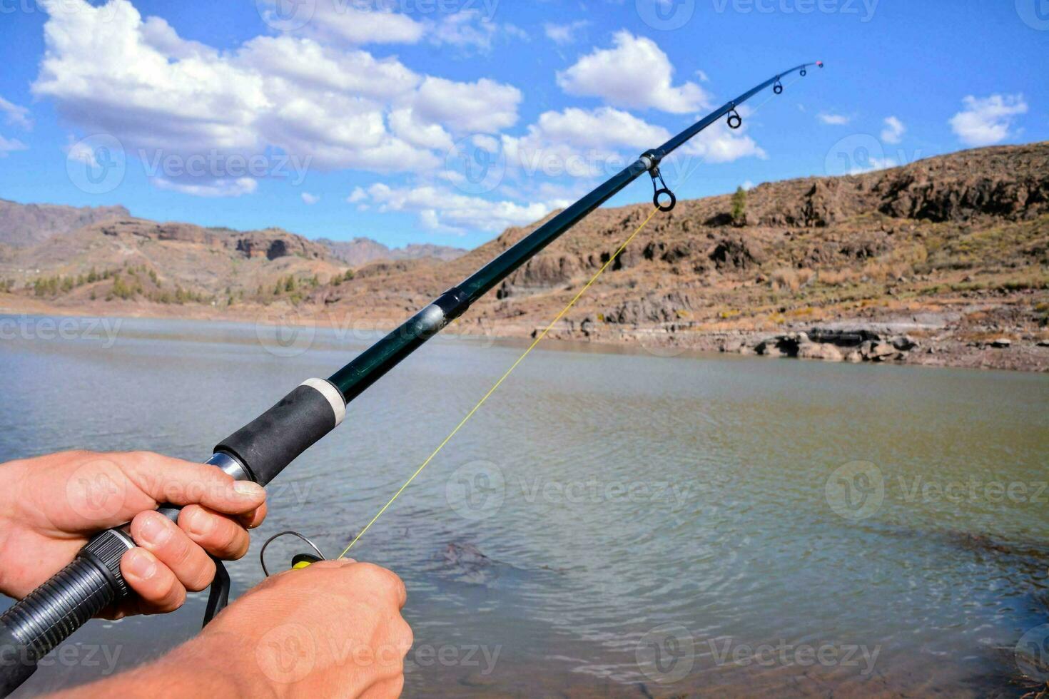 een persoon Holding een visvangst hengel in de water foto