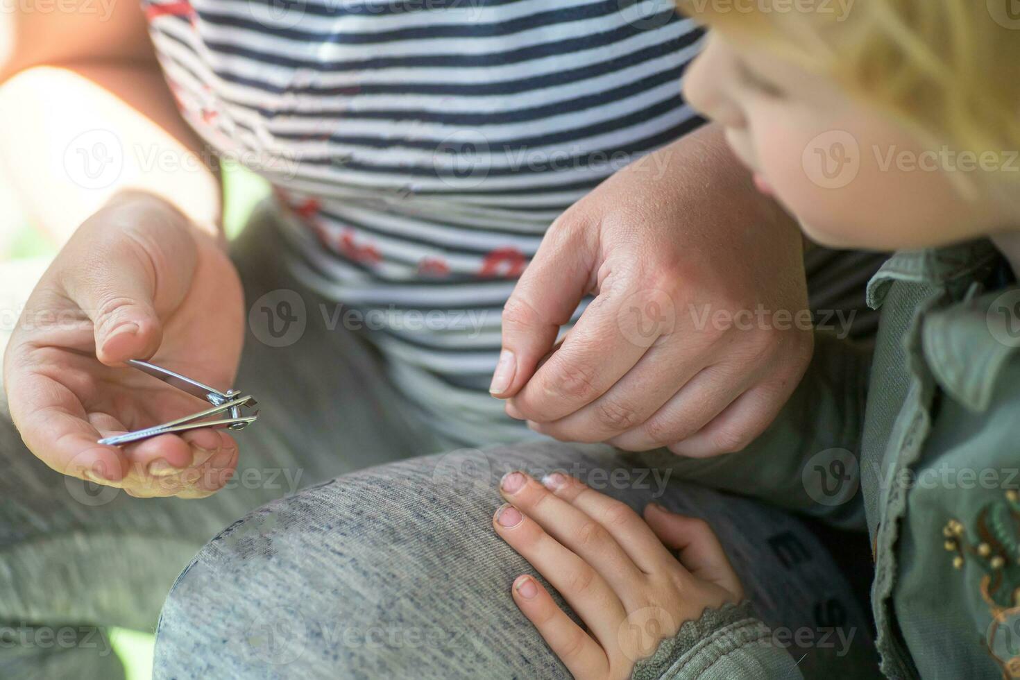 mam bezuinigingen uit de kind nagels met tang. kind zorg. persoonlijk hygiëne. foto