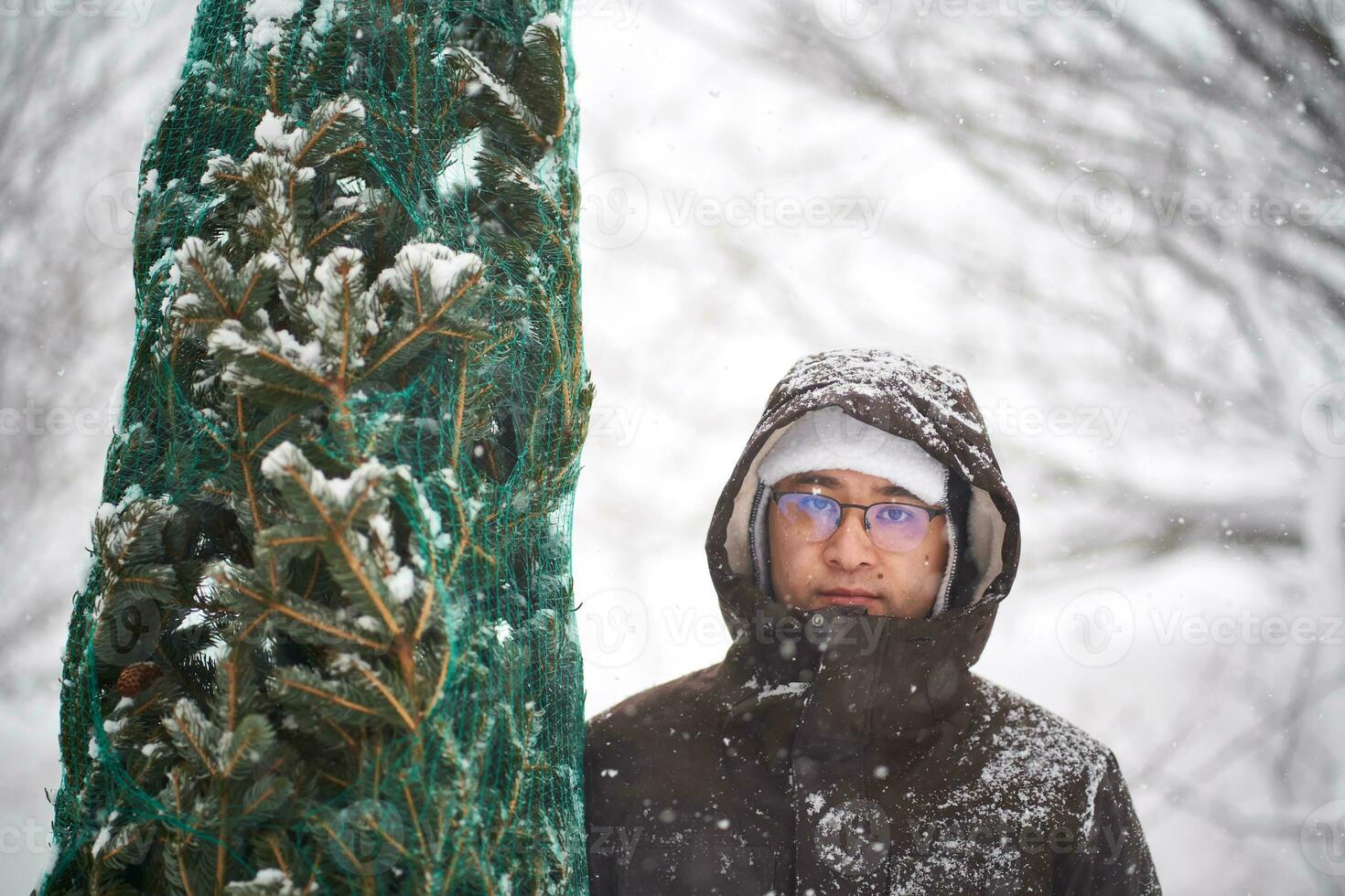 een Mens gebracht een Kerstmis boom in zijn werf gedurende een sneeuwstorm. foto