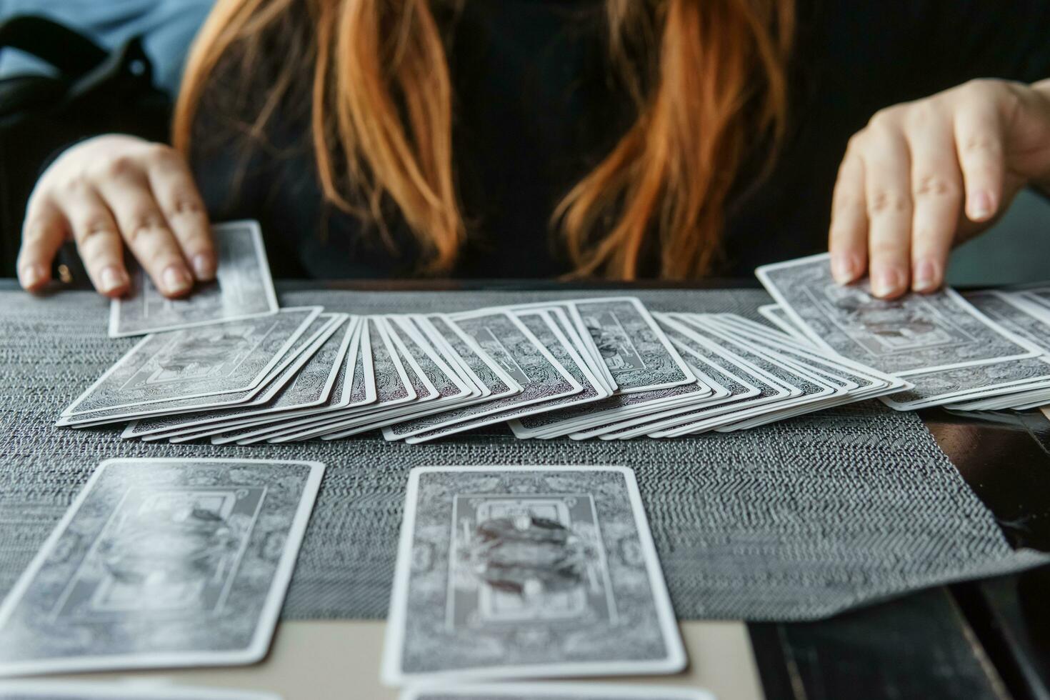 tver, Rusland - februari 11, 2023. tarot kaarten, tarot kaart waarzeggerij, esoterisch achtergrond. een vrouw maakt een lay-out Aan de kaarten Bij de tafel. waarzeggerij, voorspellingen Aan tarot kaarten. foto