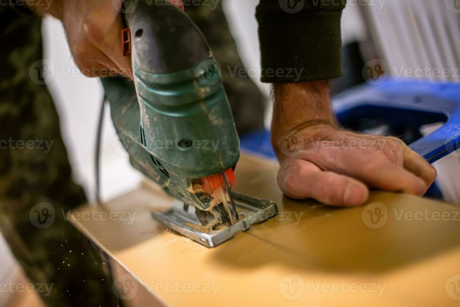 timmerman hand- gebruik makend van een elektrisch decoupeerzaag naar besnoeiing houten multiplex. de multiplex is besnoeiing in een nauwkeurig vorm geven aan, en de timmerman hand- is stabiel en zelfverzekerd. foto