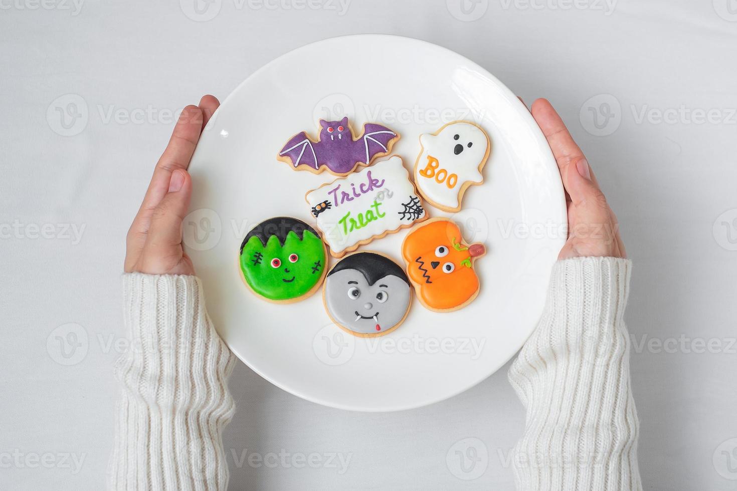 vrouw hand met plaat van grappige halloween cookies. fijne halloween-dag, truc of bedreiging, hallo oktober, herfstherfst, traditioneel, feest- en vakantieconcept foto