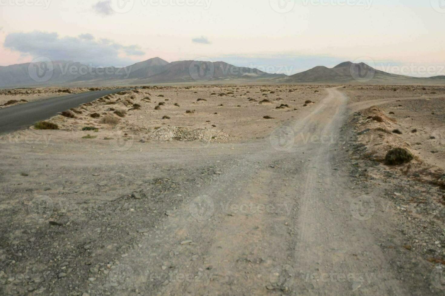 een aarde weg in de midden- van een woestijn met bergen in de achtergrond foto