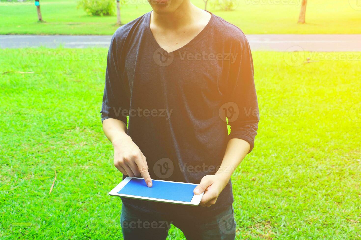 Aziatisch Mens Holding tablet computer in park foto
