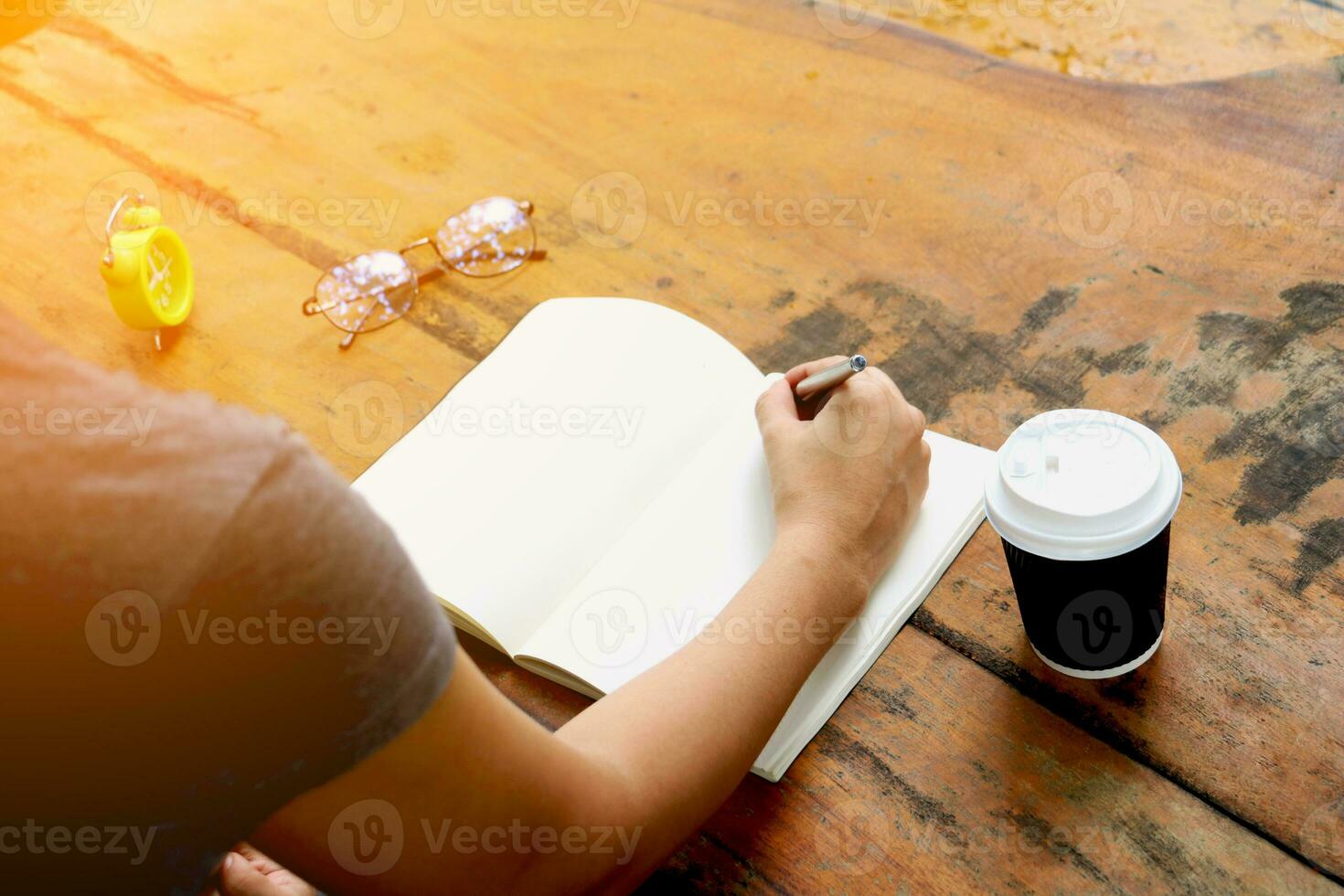 een persoon is schrijven in een notitieboekje met een kop van koffie foto