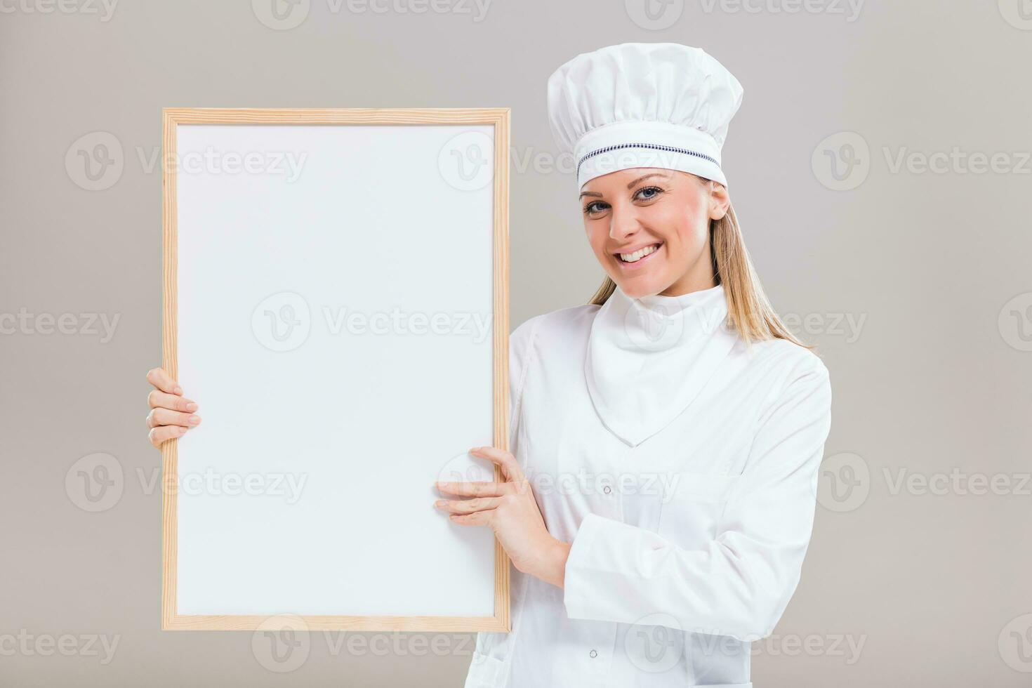 portret van mooi vrouw chef Holding whiteboard Aan grijs achtergrond. foto