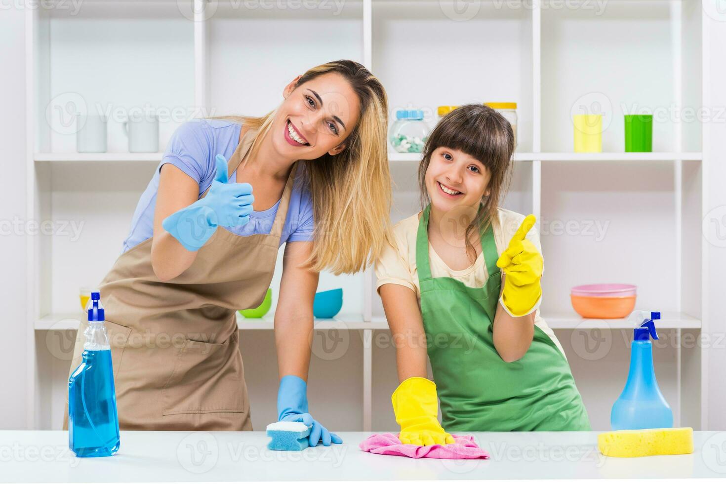 gelukkig moeder en haar dochter genieten schoonmaak samen en tonen duim omhoog. foto