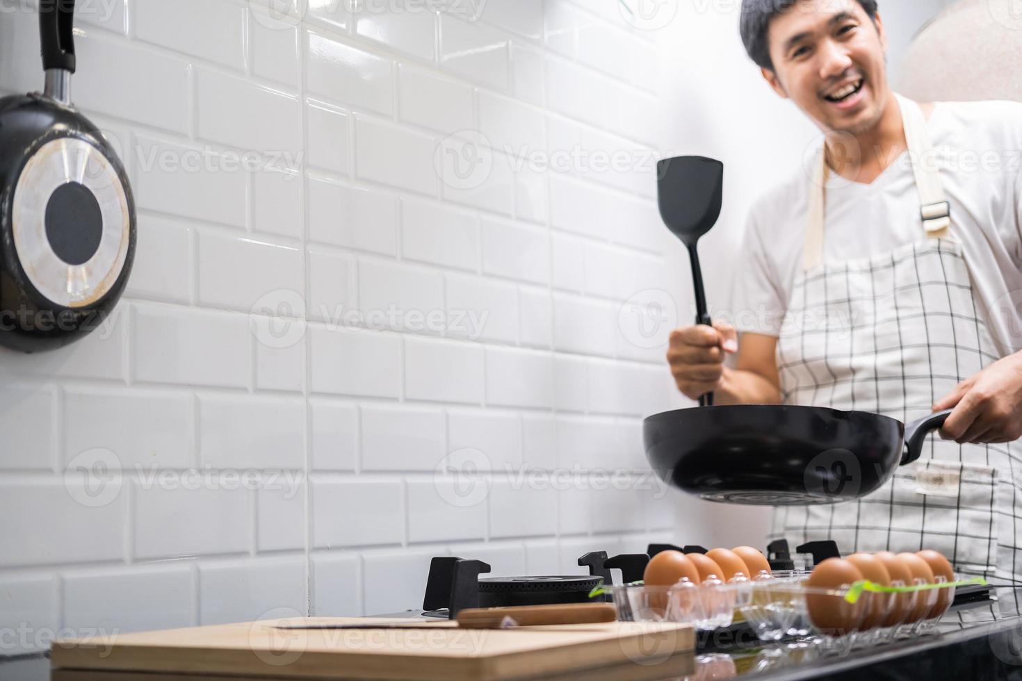 Aziatische chef-kok gebakken eieren op pan naar Thais eten in de keuken op gasfornuis de olie in pan kokende eieren en varkensvlees gekookt. voor het serveren aan het gelukkige gezin om samen thuis te eten foto