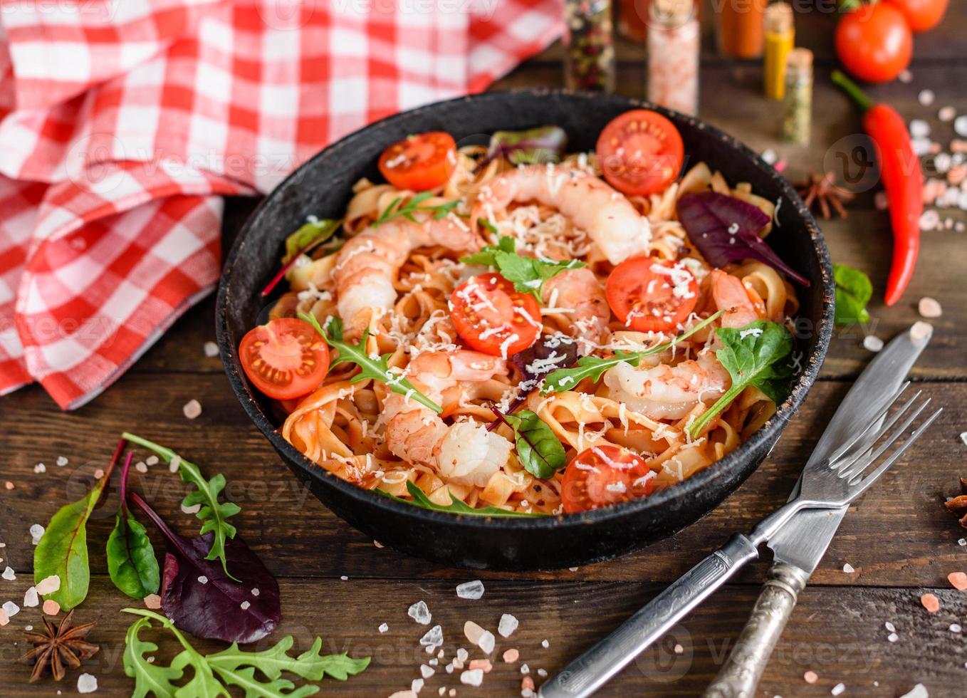 Lekkere pasta met garnalen en tomaat op een koekenpan foto