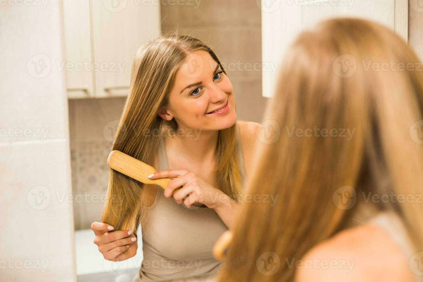 mooi vrouw kammen haar haar- in de badkamer foto