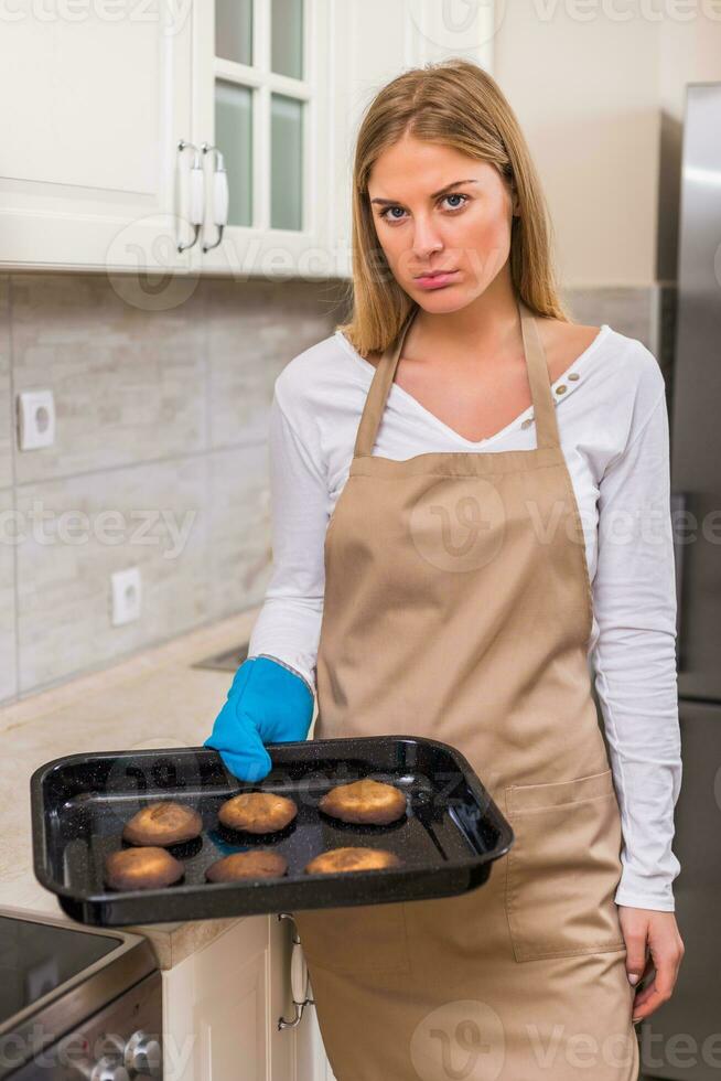 verdrietig huisvrouw Holding dienblad met verbrand koekjes foto