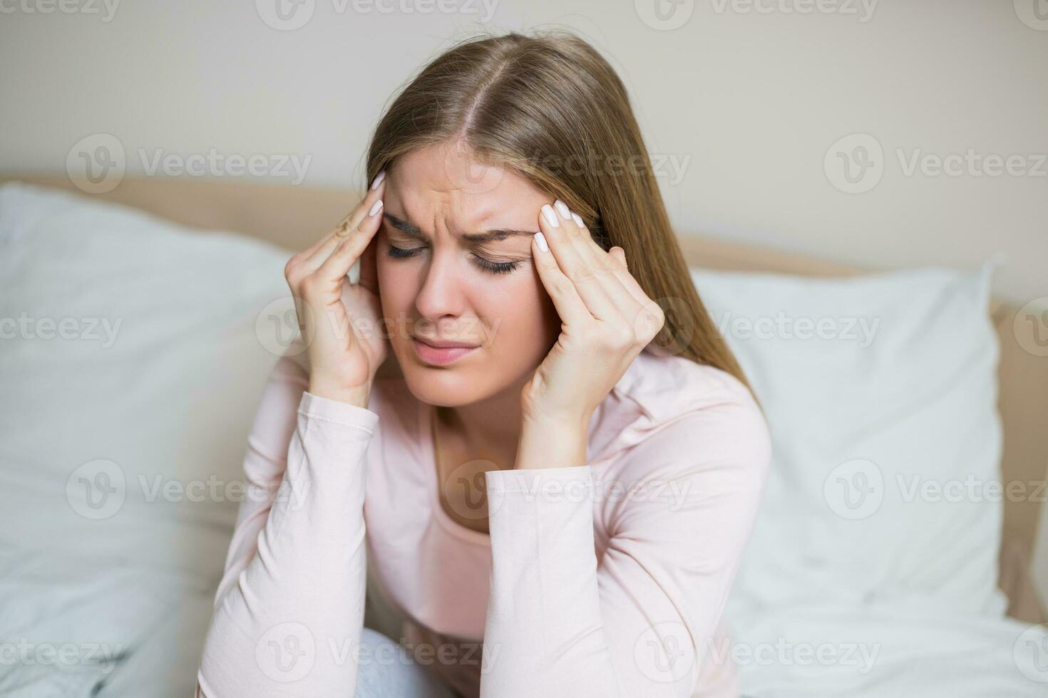 vrouw hebben sterk hoofdpijn terwijl zittend in slaapkamer foto