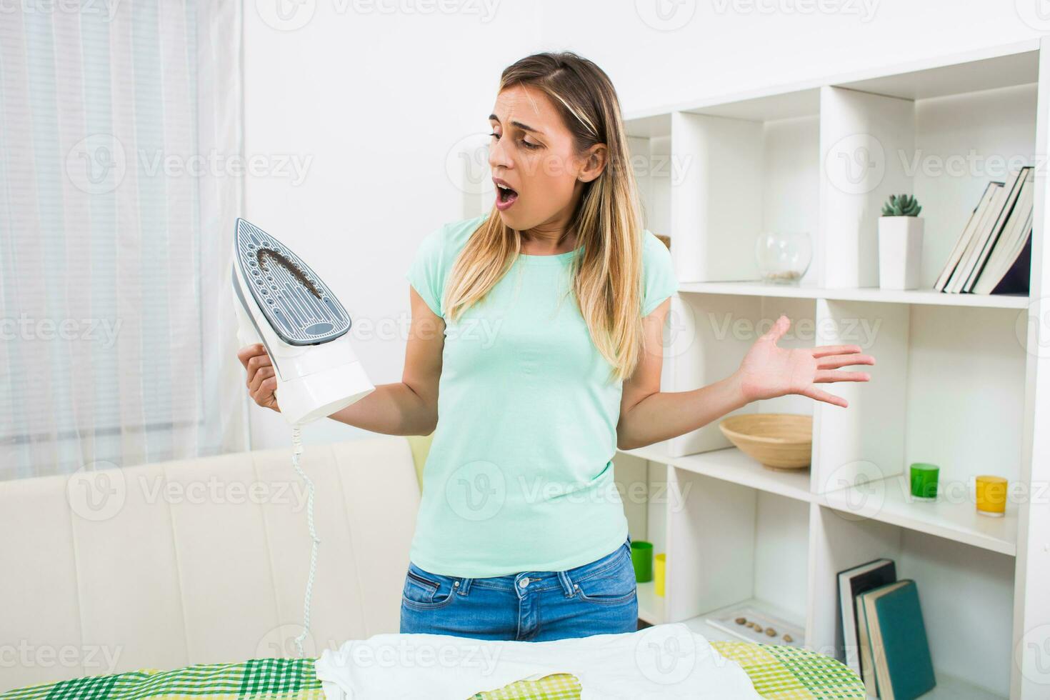 ten einde raad vrouw heeft beschadigd haar ijzer en gemaakt een gat Aan haar t shirt. foto