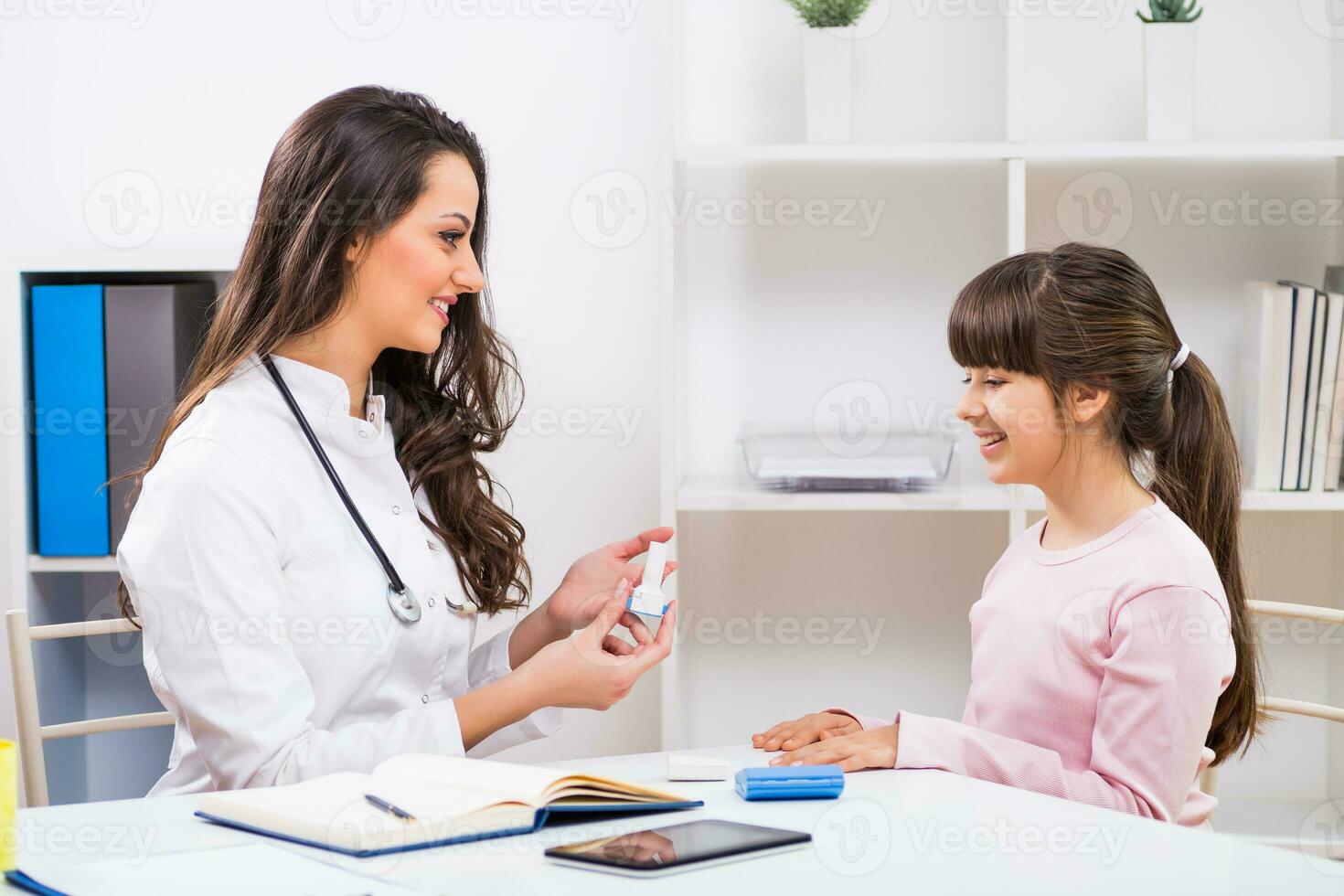 vrouw dokter tonen hoe naar gebruik inhalator naar een kind Bij de medisch kantoor foto