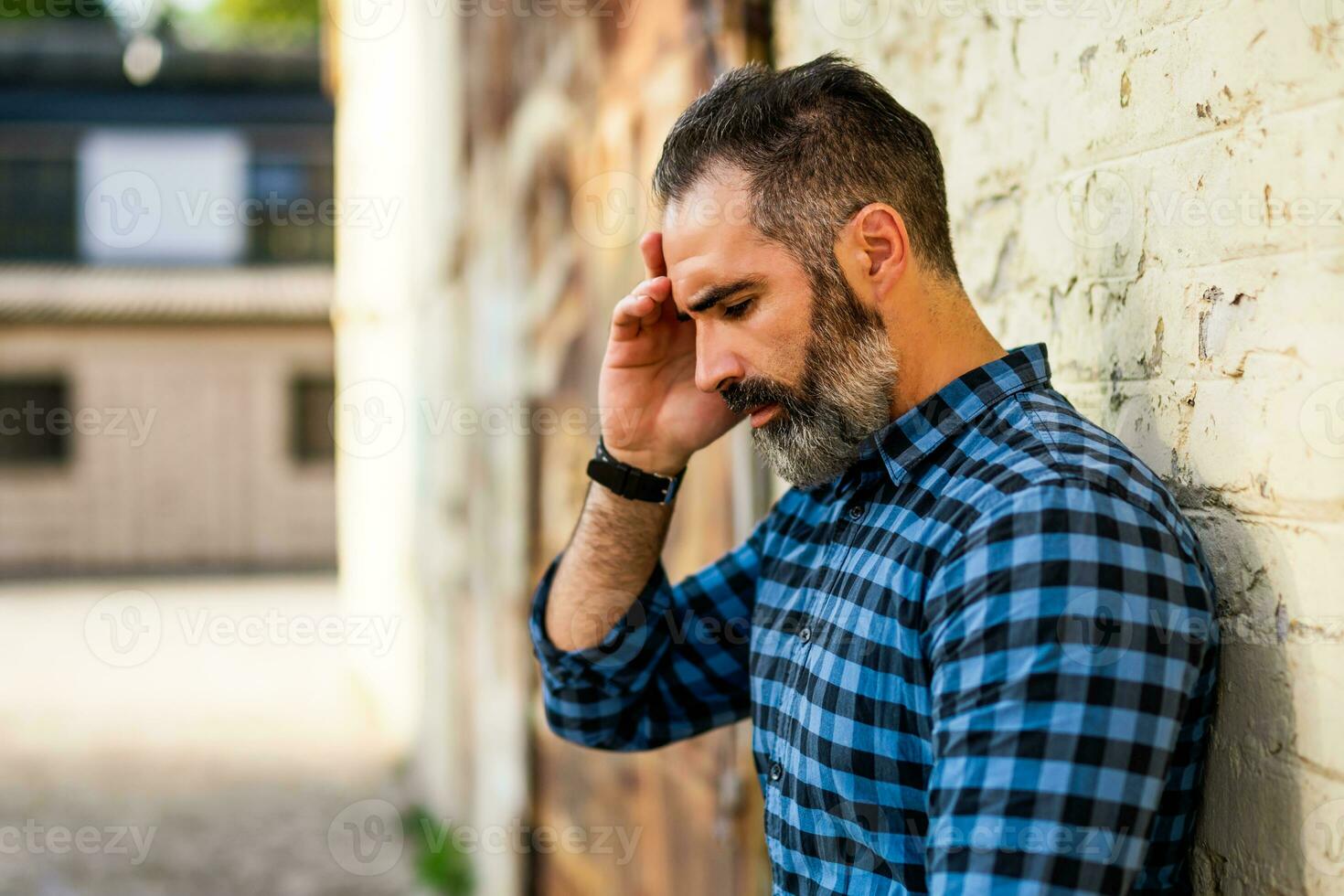 depressief zakenman met baard staand in voorkant van muur buiten de deur foto