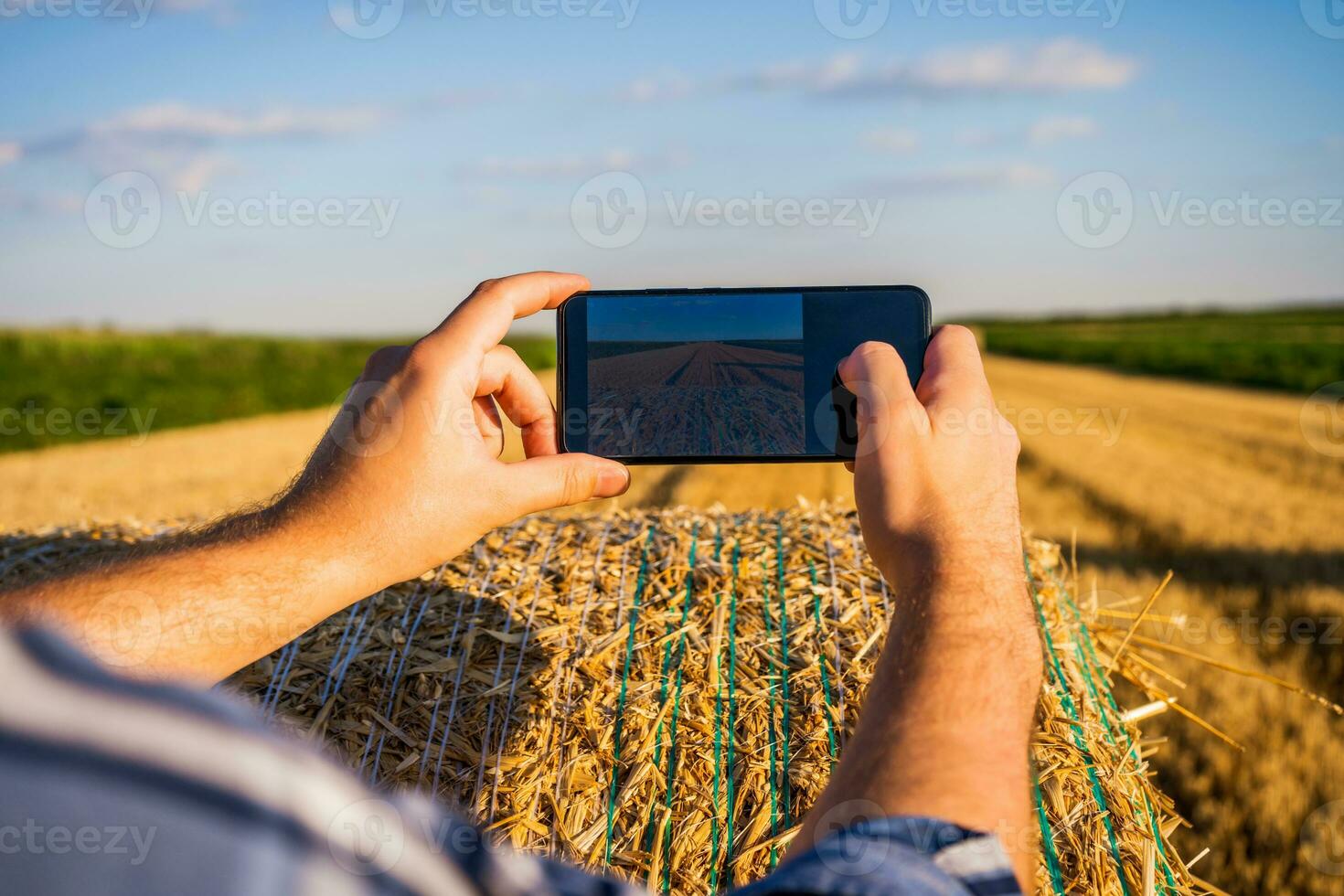 boer is fotograferen met telefoon rietje na geslaagd oogsten foto