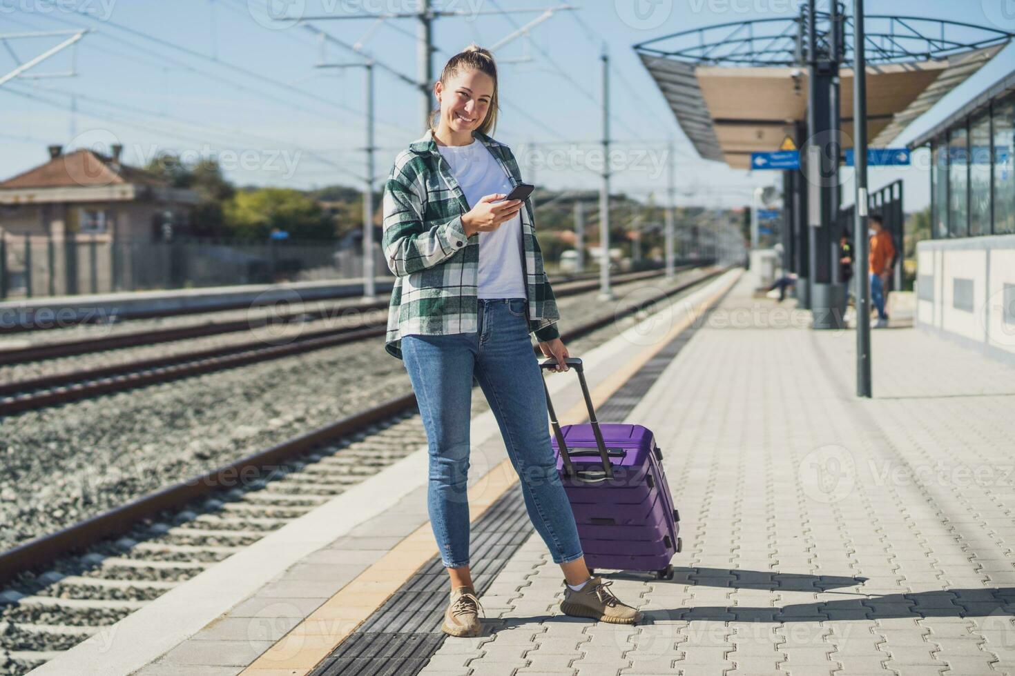 gelukkig vrouw gebruik makend van mobiel telefoon Aan een trein station foto