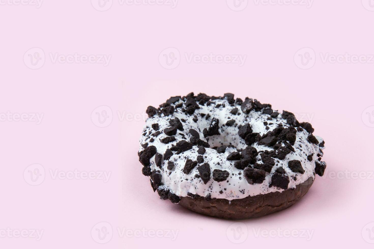 donut in donker chocola glazuur met stukken van chocola Aan een roze achtergrond. hoog kwaliteit foto