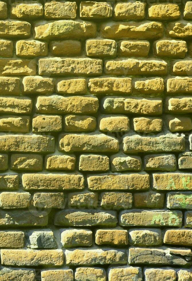 verticaal muur structuur van meerdere rijen van heel oud metselwerk gemaakt van rood steen. verbrijzeld en beschadigd steen muur met geknepen hoeken foto