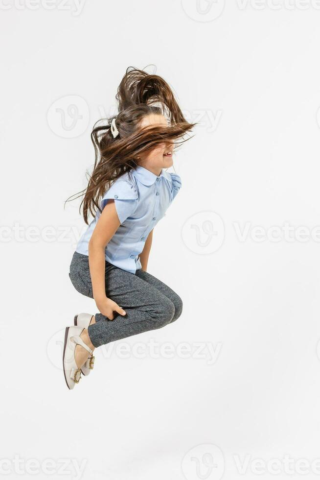 gelukkig schoolmeisje jumping hoog Aan wit achtergrond foto