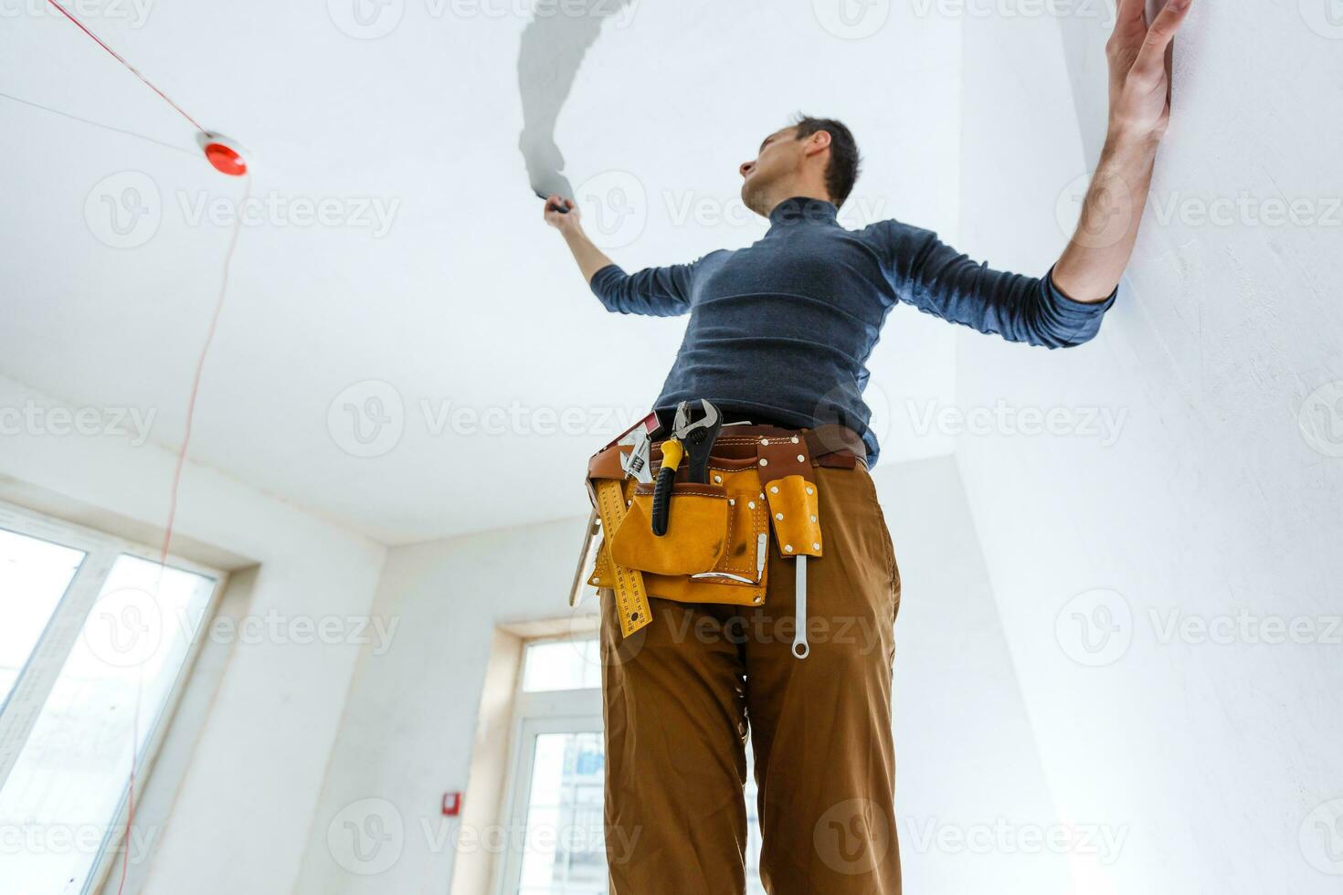 dertig jaar oude arbeider met stukadoorsgereedschap in een huis. stukadoor renovatie van binnenmuren en plafonds met vlotter en pleisterwerk. foto