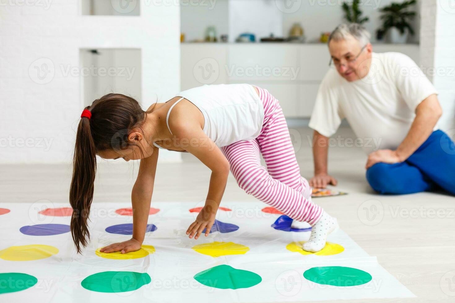 weinig meisje en opa Speel twister Bij huis foto