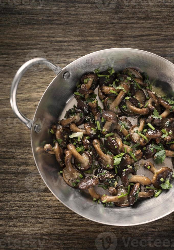 shiitake-paddenstoelen gebakken met knoflook en kruiden in metalen pan foto