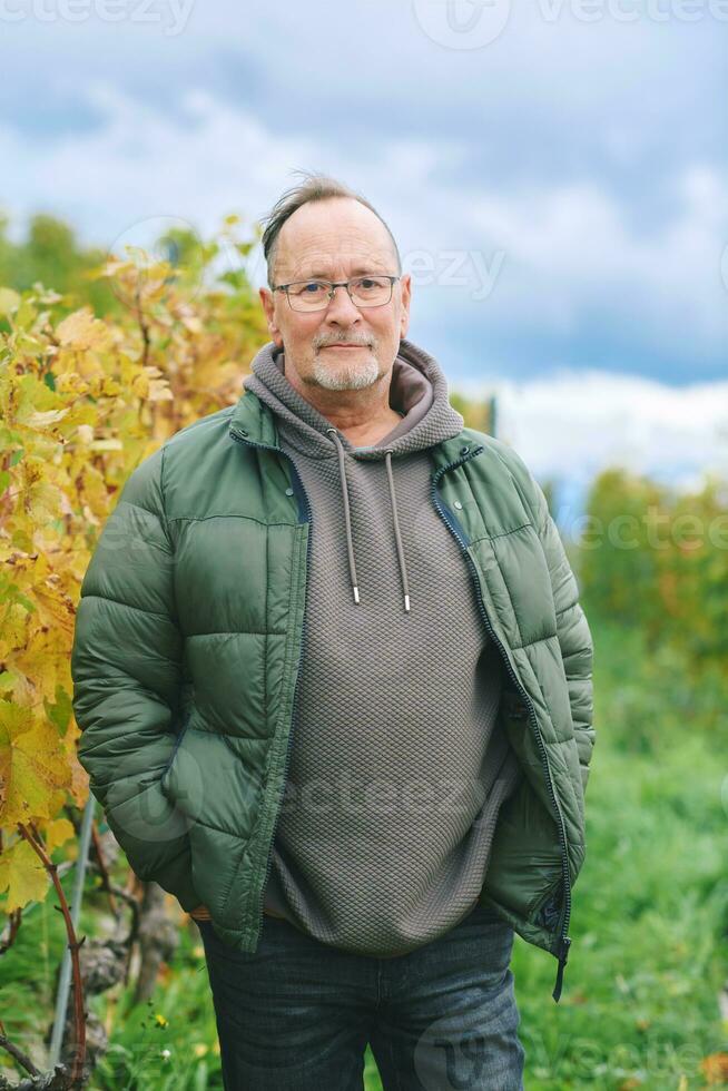 buitenshuis portret van midden- leeftijd 55 - 60 jaar oud Mens genieten mooi hoor herfst dag in wijngaarden, gezond en actief levensstijl foto