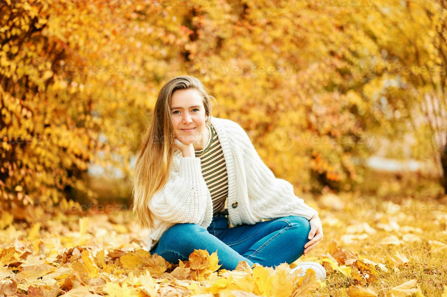 herfst portret van jong gelukkig meisje zittend Aan grond met geel gebladerte achtergrond, gezond levensstijl foto