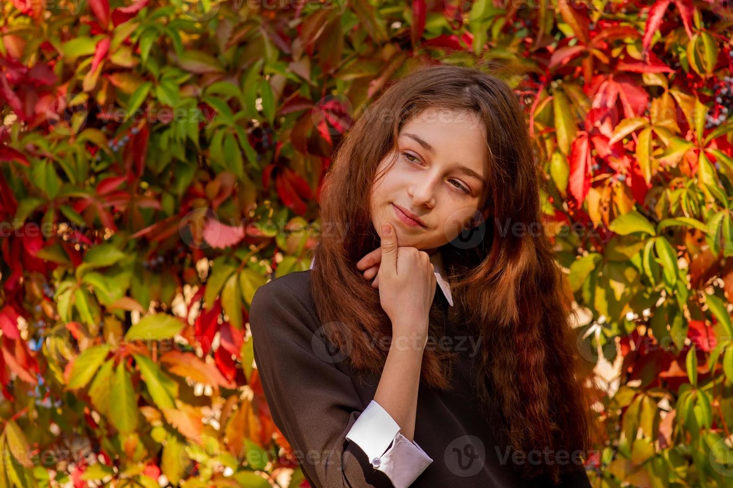 schoolmeisje in schoolkleren in de natuur op een achtergrond van herfstbladeren. meisje 11 jaar oud. foto