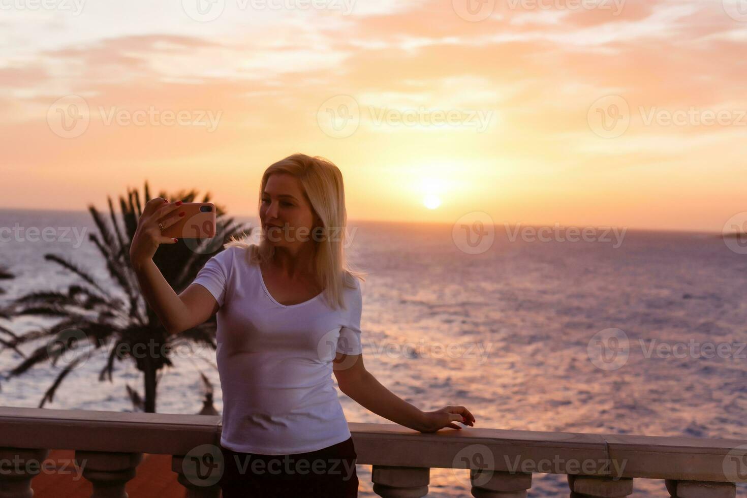 vrouw bewonderend zonsondergang van haar balkon foto