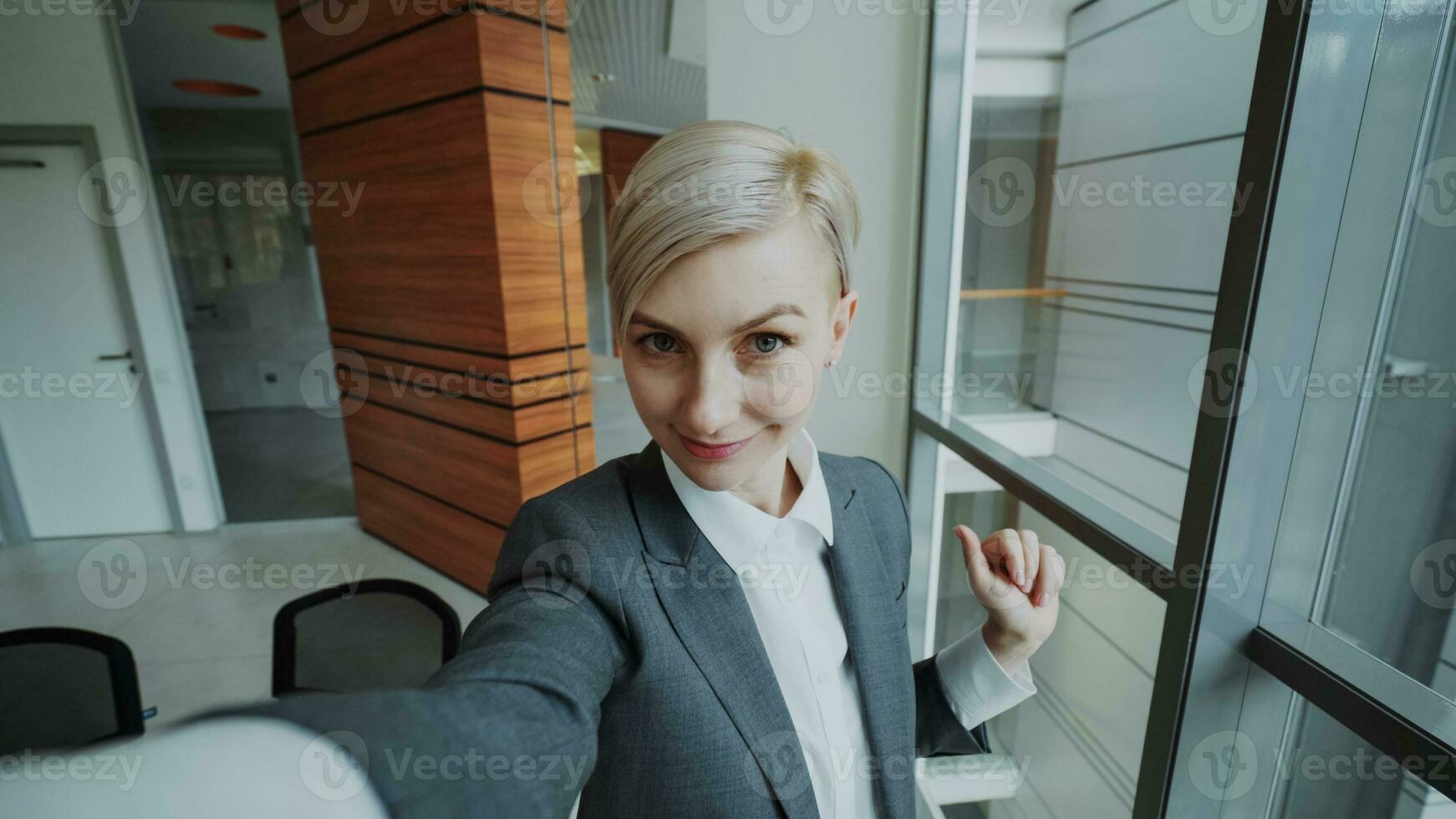 pov van jong zakenvrouw in pak nemen een selfie foto Holding smartphone en hebben pret in modern kantoor binnenshuis