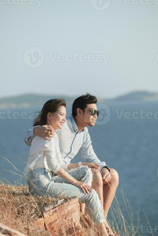 jong paren ontspannende Aan hoog berg tegen blauw zee achtergrond foto