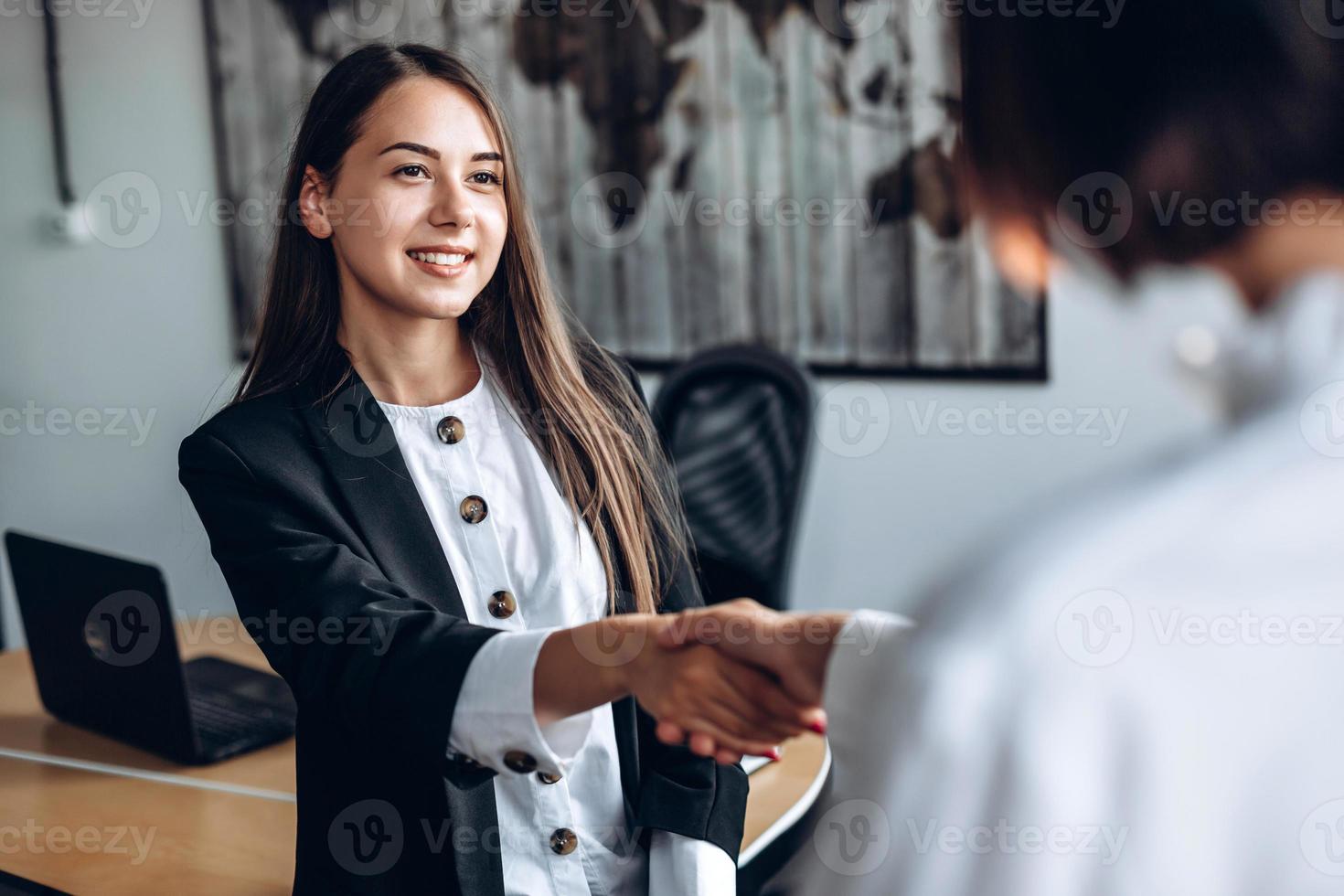 mooi, succesvol meisje schudt de hand van haar partner. concept van het ondertekenen van een overeenkomst foto