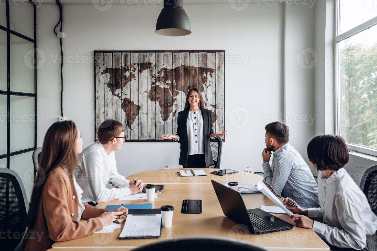 jong aantrekkelijk meisje dat een rapport maakt voor haar collega's. werkvergadering op kantoor foto