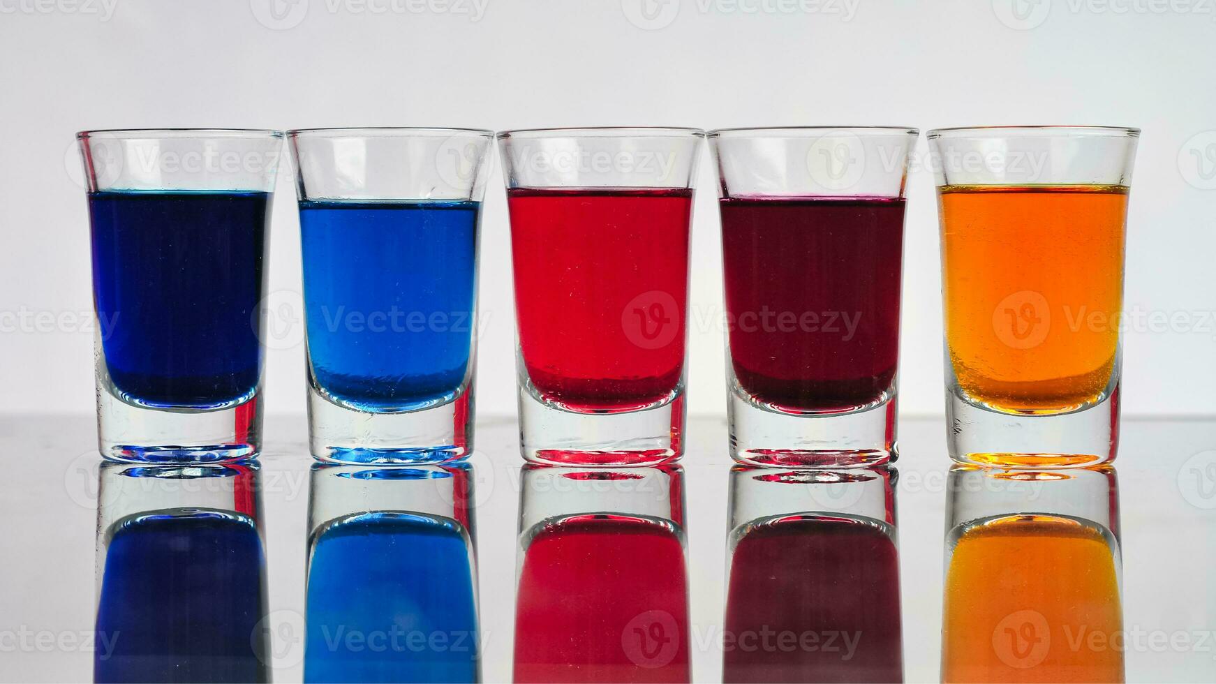klein bril gevulde met kleurrijk water zijn netjes geregeld Aan een geïsoleerd wit achtergrond foto