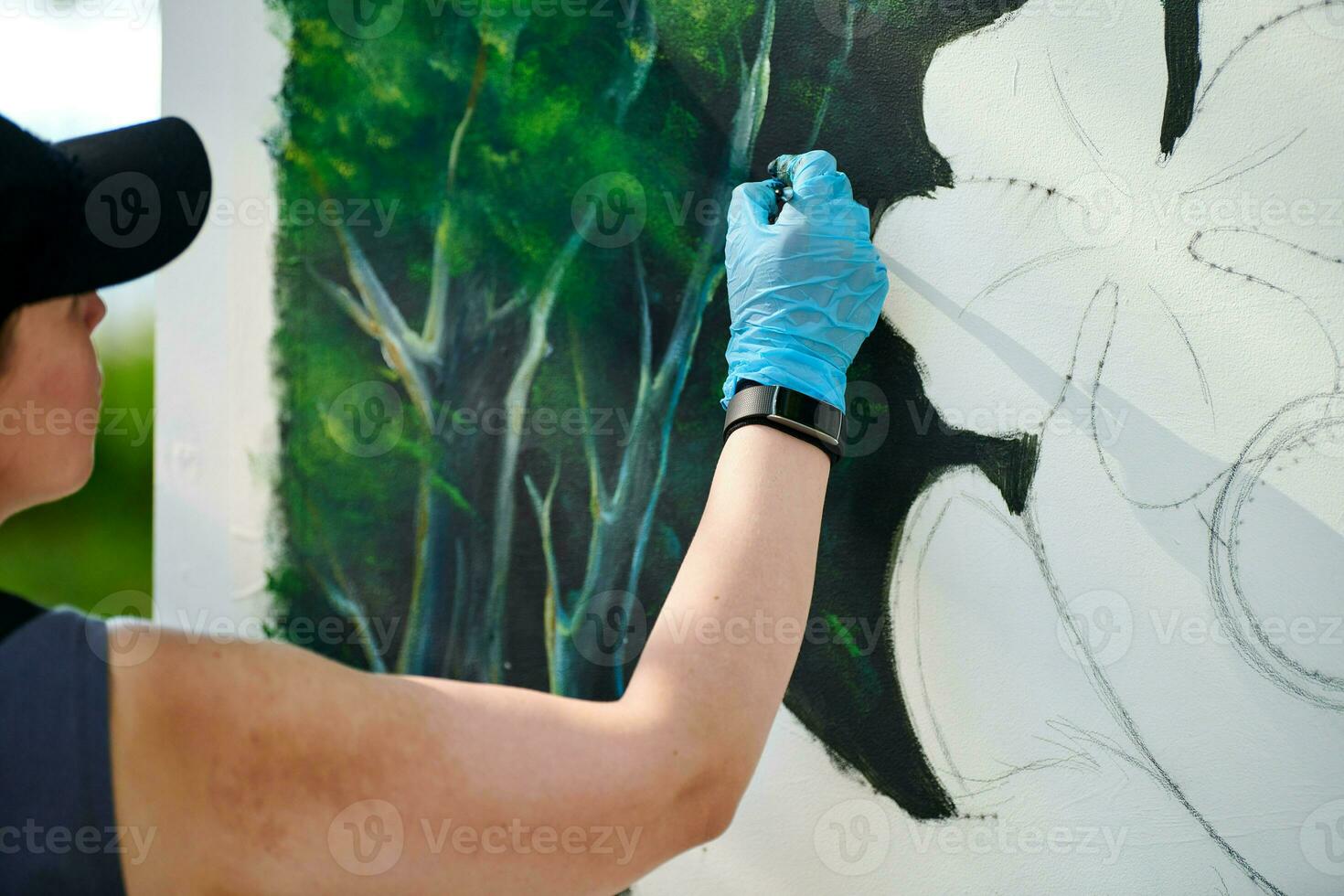 meisje artiest hand- houdt verf borstel en trekt groen natuur landschap Aan canvas foto