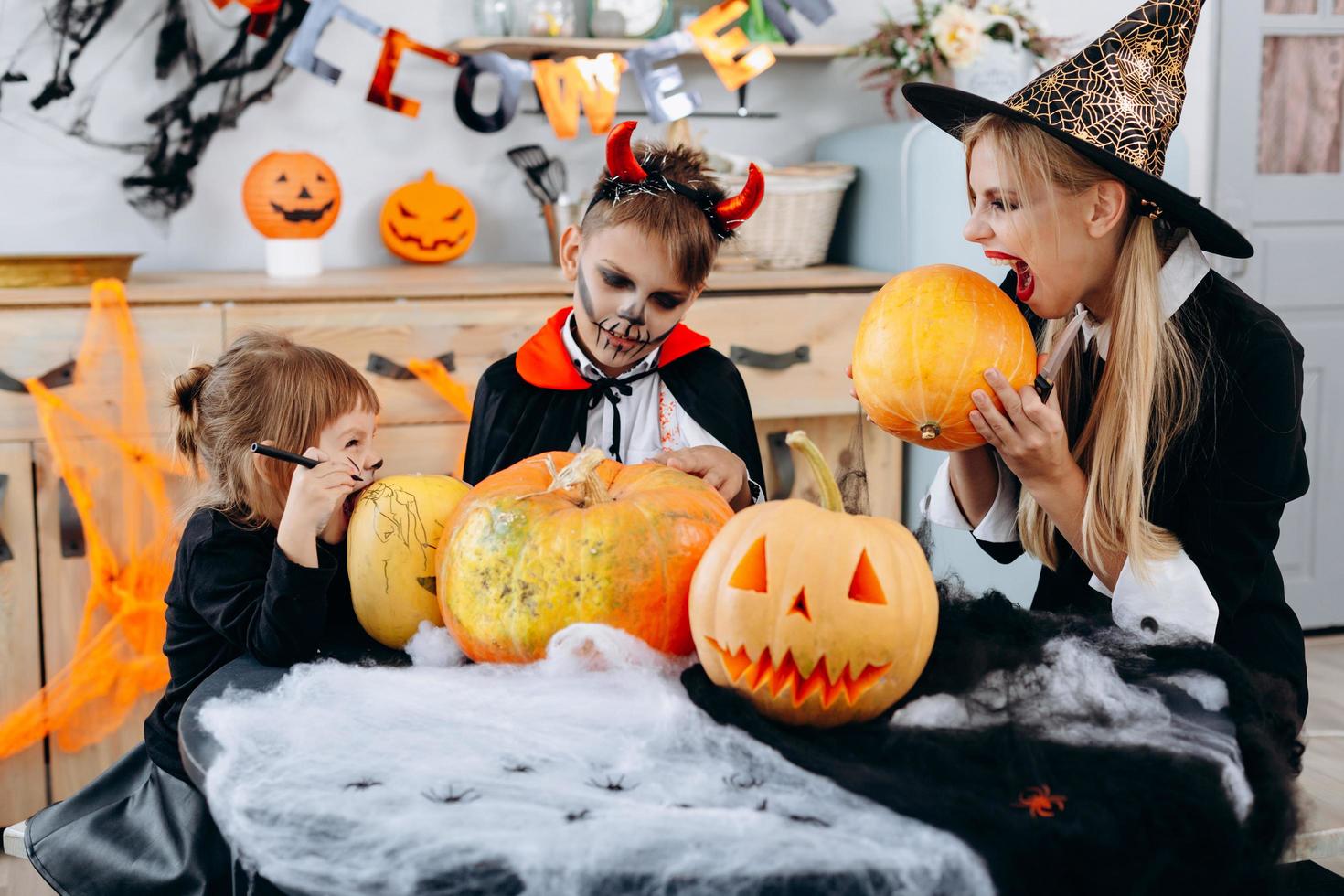 familie hebben grappige tijd thuis. moeder en dochter gaan een pompoen bijten - halloween concept foto