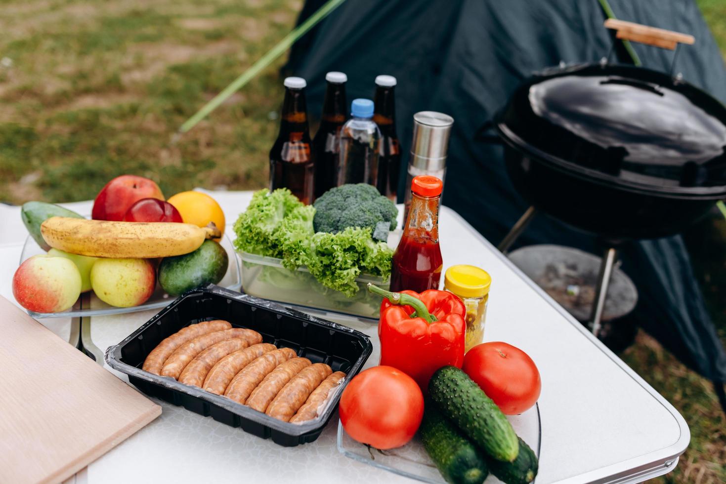 bier, worstjes en verse groenten op tafel buiten. - kamperen foto