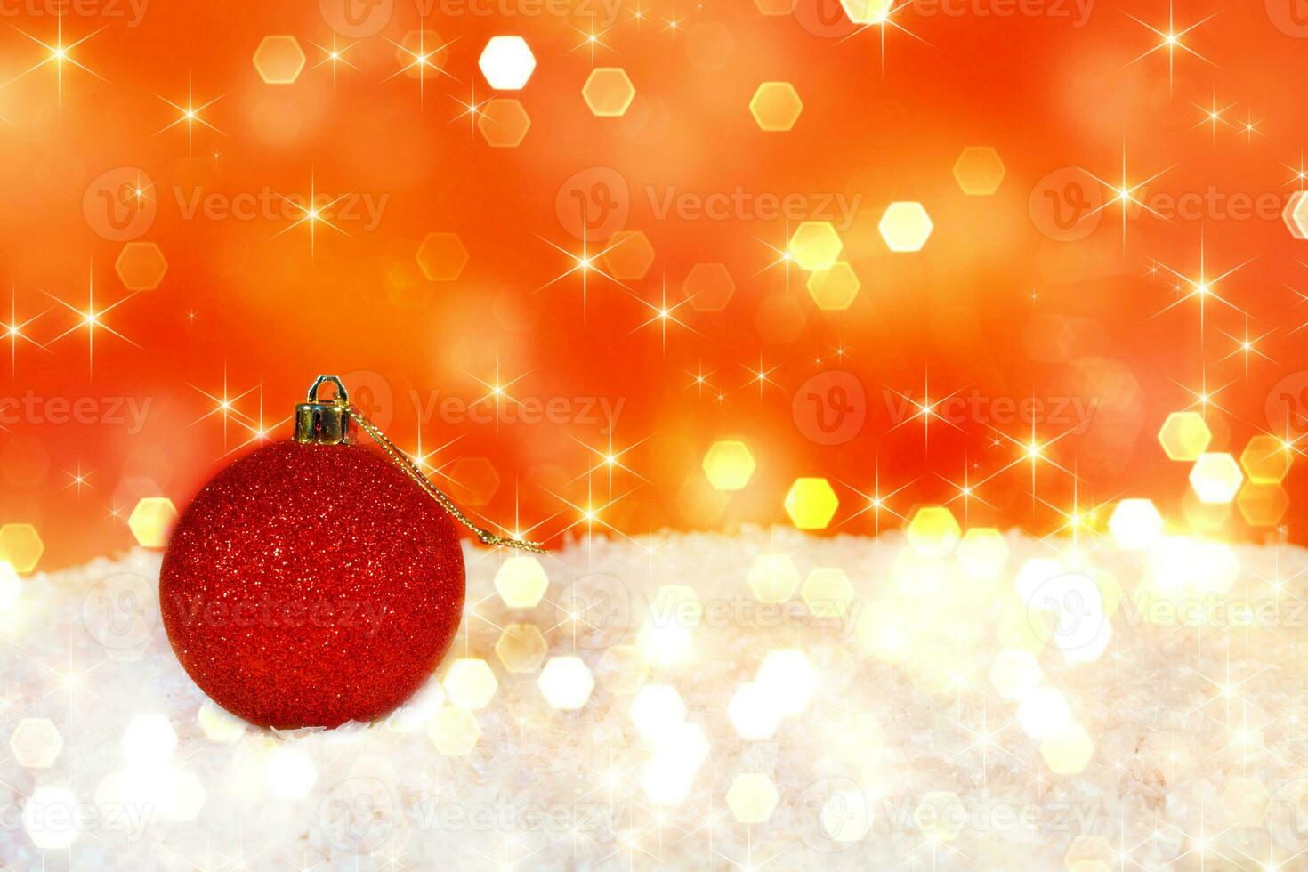 rood Kerstmis bal voor decoreren een Kerstmis boom Aan sneeuw en een rood achtergrond met bokeh. ruimte voor uw tekst foto