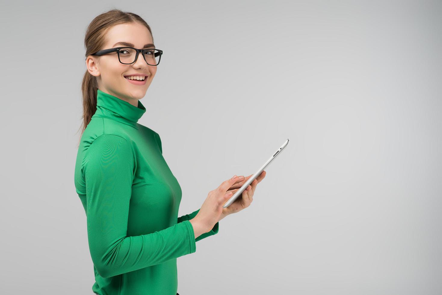 vrolijk profielmeisje dat een tablet in haar handen houdt en glimlacht foto