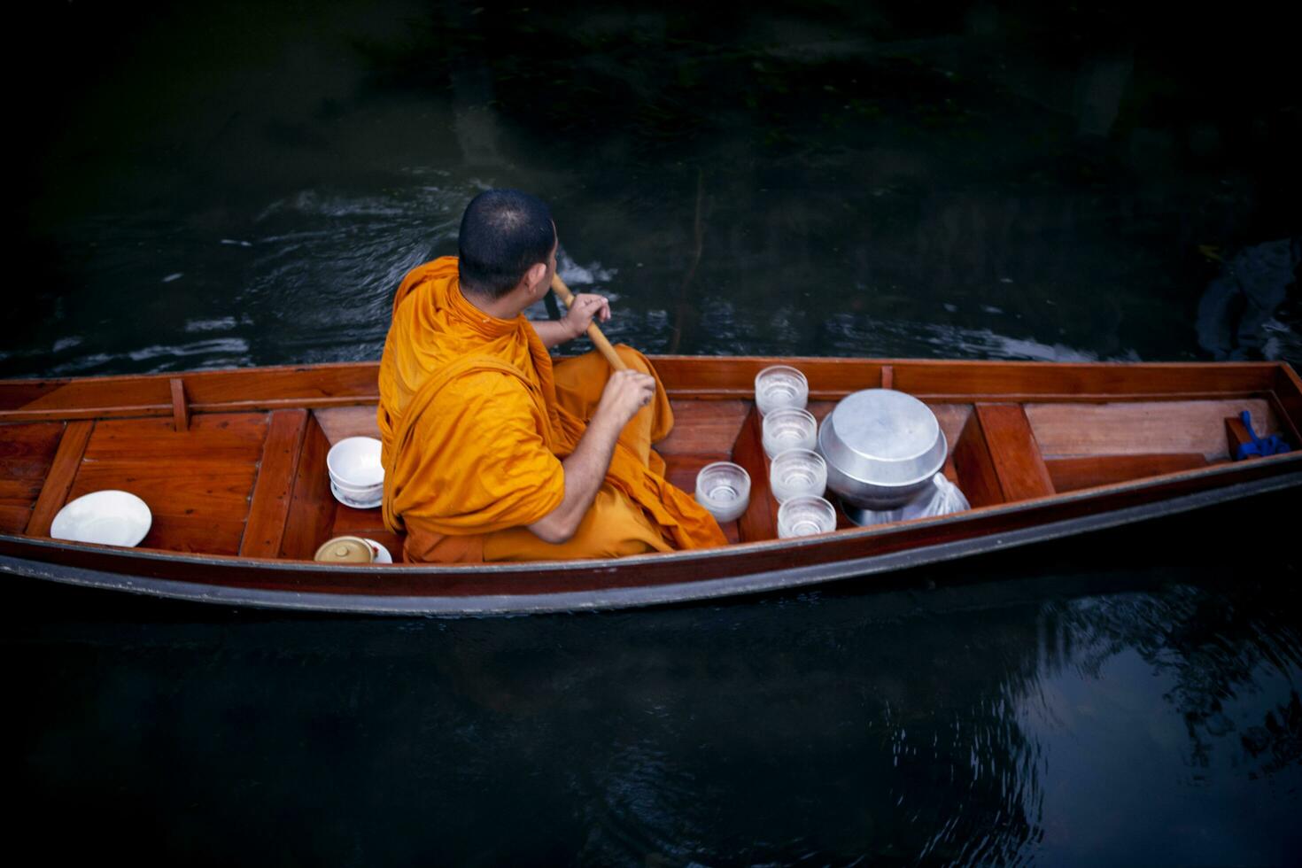 Thais monnik het zeilen hout boot in kanaal voor ontvangen voedsel aanbieden van pelgrim foto