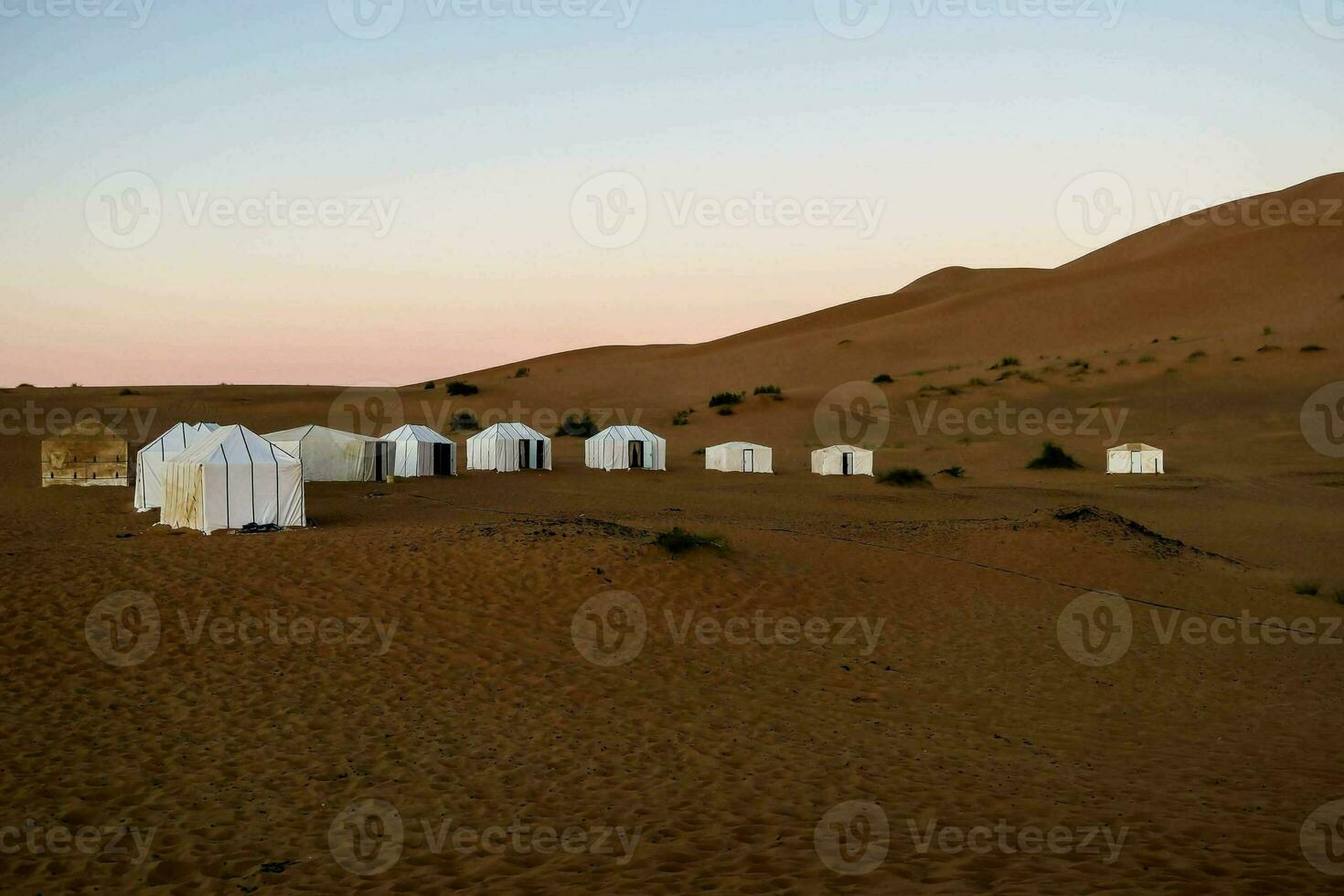 de tenten zijn in de woestijn met zand duinen foto