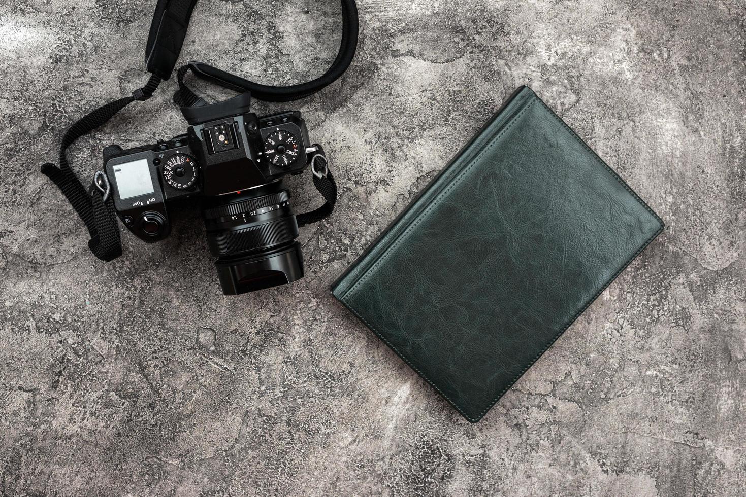 fotocamera en een notitieboekje liggend op een gipsen achtergrond foto