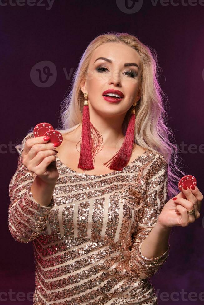 blond vrouw met een perfect kapsel en helder bedenken is poseren met het gokken chips in haar handen. casino, poker. foto